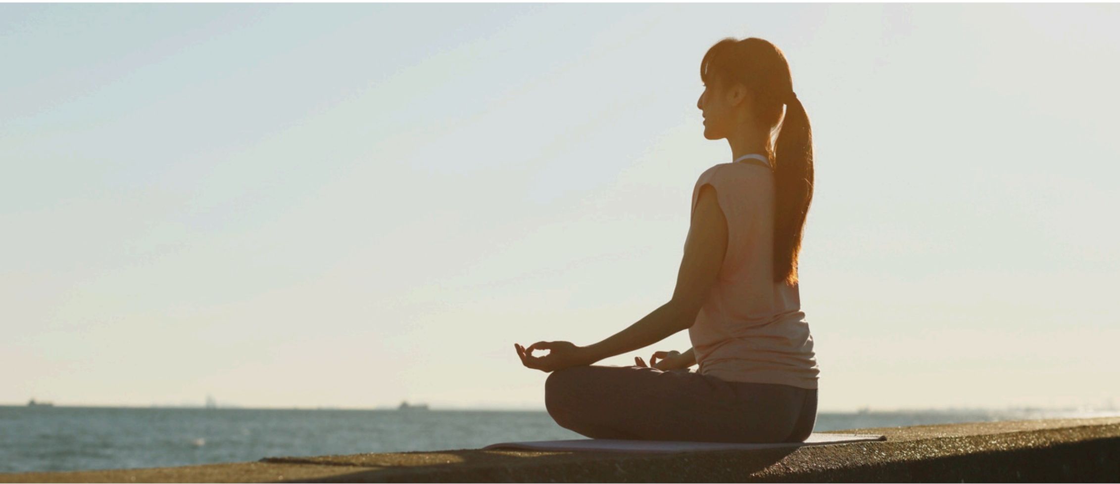 Frau in meditativer Haltung am Wasser